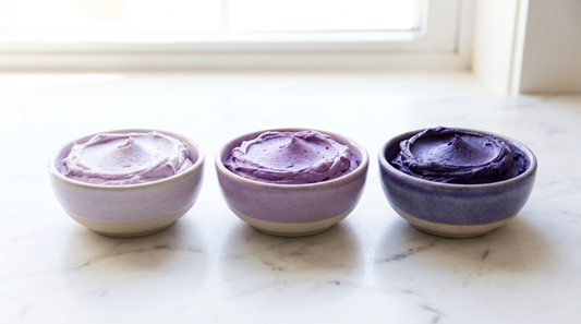 Three bowls of purple buttercream in progressively deeper shades