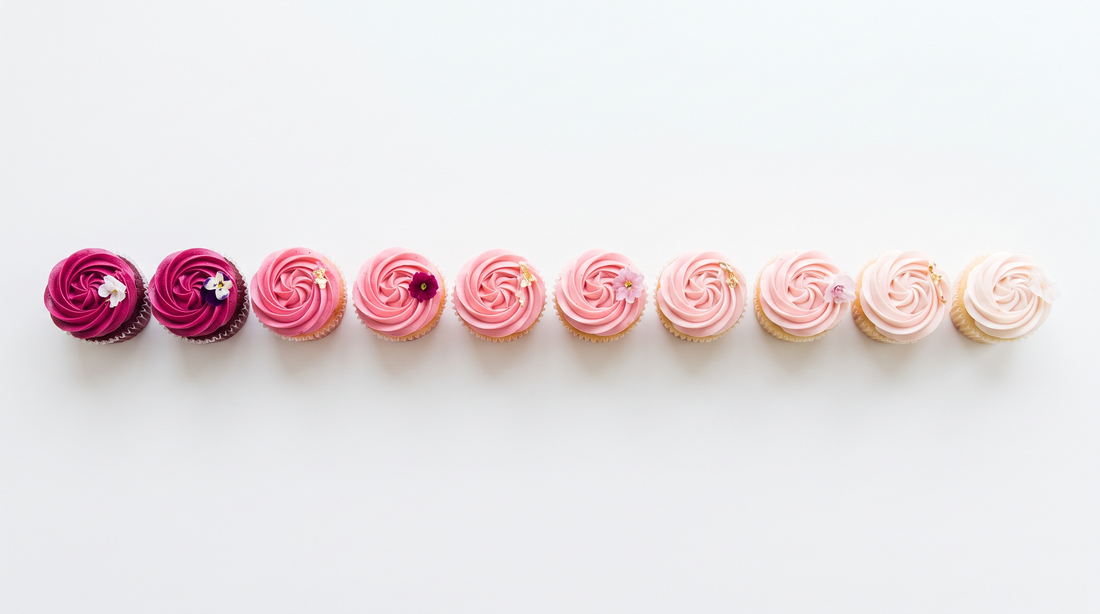 A row of cupcakes frosted in a gradient from deep magenta to pale blush