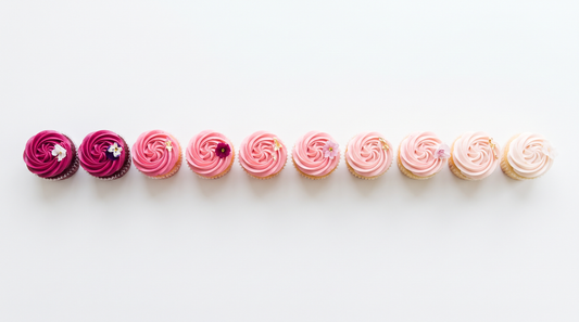 A row of cupcakes frosted in a gradient from deep magenta to pale blush