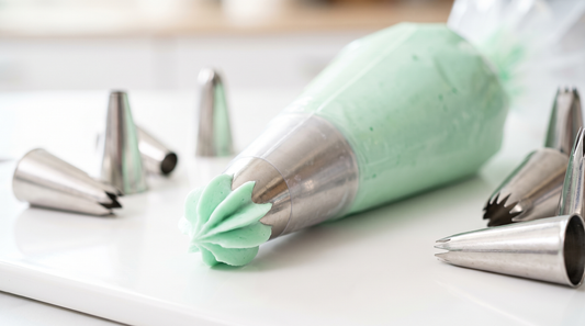 A sharp rosette of mint green buttercream being piped with a star tip