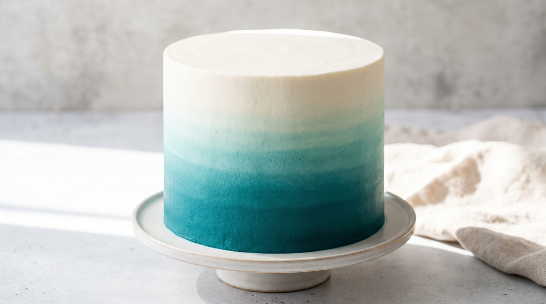 A smooth ombre frosted cake shading from deep teal at the base to white at the top