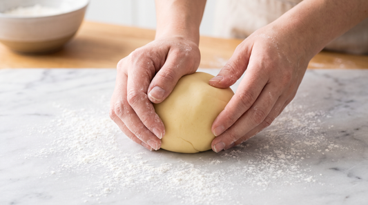Hands kneading a smooth ball of evenly colored pastel yellow fondant
