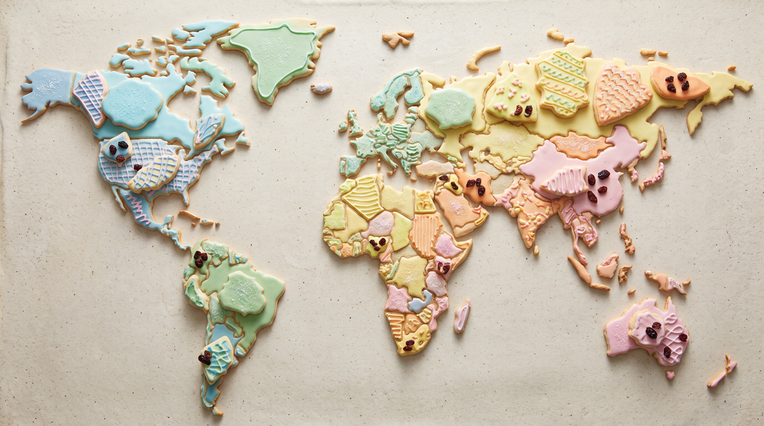 A flat lay of colorful frosted cookies arranged in scattered clusters across a pale surface